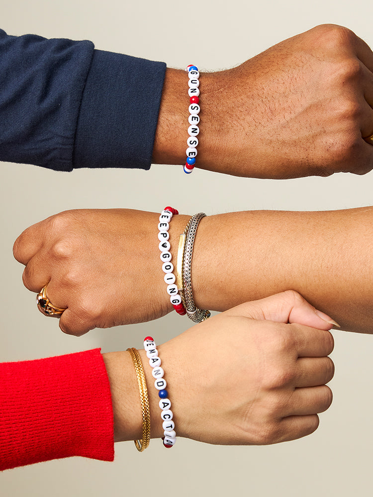 Three people wearing red, white, and blue beaded friendship bracelets that read: GUN SENSE, KEEP GOING, and DEMAND ACTION.