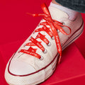 Red shoelaces with repeated white text that reads Keep Going on a white converse sneaker.
