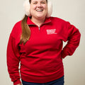 Front view of woman wearing a quarter-zip collared sweatshirt with a small white Moms Demand Action for Gun Sense in America logo printed on left chest.