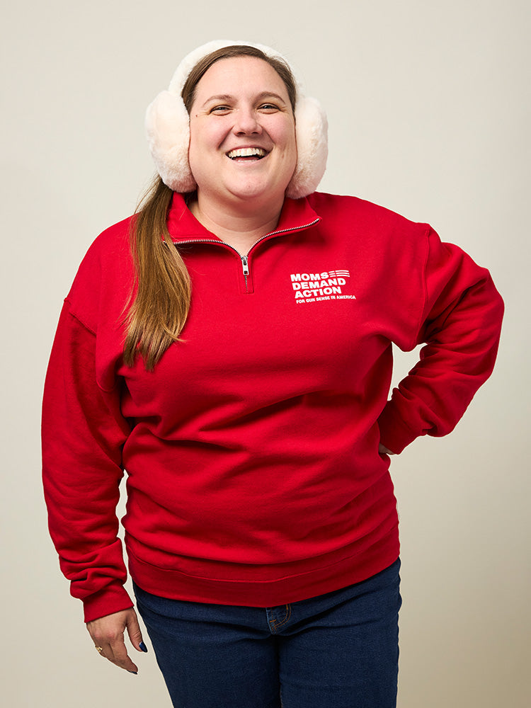 Front view of woman wearing a quarter-zip collared sweatshirt with a small white Moms Demand Action for Gun Sense in America logo printed on left chest.