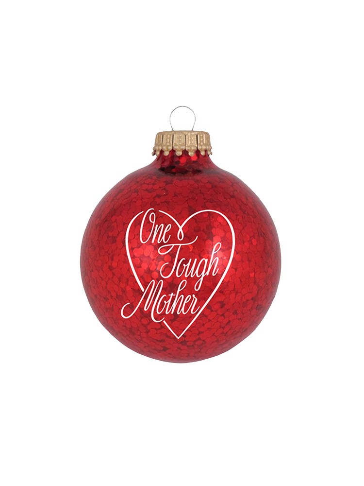 Red, glittery, round plastic ornament with One Tough Mother printed in script font in white on one side.