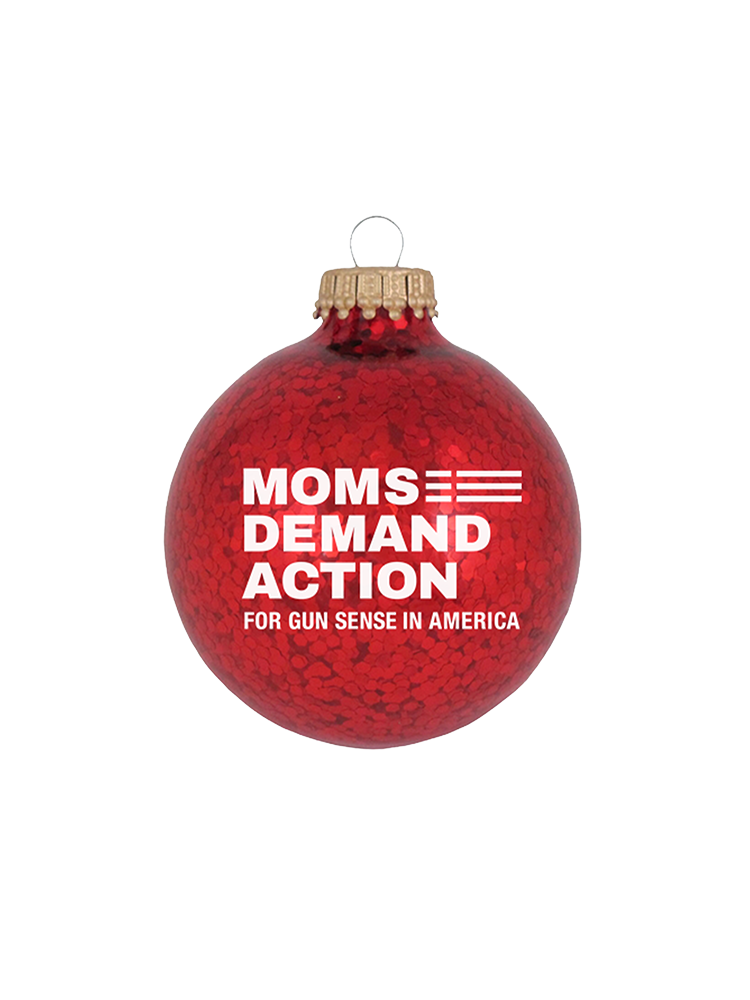Red, glittery, round plastic ornament with white Moms Demand Action logo printed on one side.