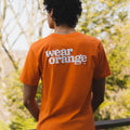 Orange short-sleeve unisex t-shirt, back view. The Wear Orange logo is printed large in white.