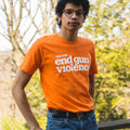 Orange short-sleeve unisex t-shirt, front view. In large white print across the chest, it reads: we can end gun violence. The dot of the i in violence is printed in light orange.